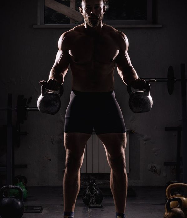 Man performing a controlled strength exercise in a dark, focused environment.